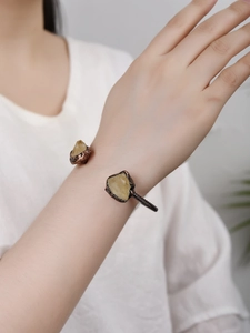 Detail of vintage bronze adjustable cuff featuring two raw yellow crystals on a model wrist