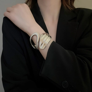 Close-up of irregular hollow silver bangle with polished finish on model suit