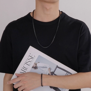 Close-up of a man wearing a black stainless steel chain necklace and matching bracelet set