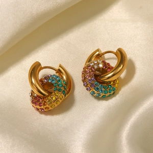 Macro shot of 18k gold earrings with colorful rhinestones on elegant silk fabric
