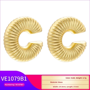 Detailed view of gold-tone brass C-shaped hoop earrings featuring a ribbed spiral texture
