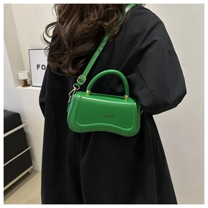 Side view of woman in black coat wearing a green PU leather crossbody bag with fashion text