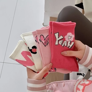 Detailed shot of pink cotton crew socks featuring YEAH text and a heart pattern