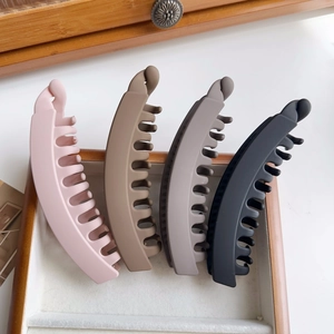 Matte finish banana hair clips in four neutral colors neatly arranged on a wooden tray