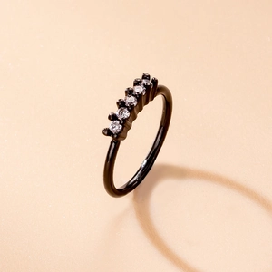 Close-up of black nose ring with five inlaid clear zircons on a peach background