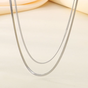 Detailed close-up of a silver double-layered chain necklace with flat blade and link chains