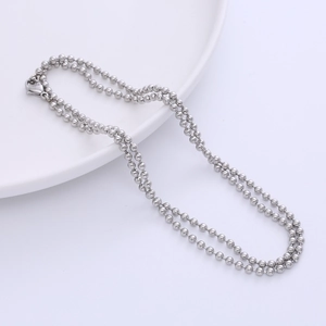 Polished stainless steel ball chain necklace with lobster clasp on a white plate