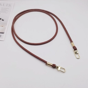 Dettaglio della tracolla in pelle PU marrone con ganci girevoli dorati e design vintage