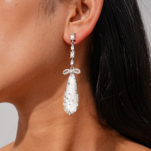Détail d'une boucle d'oreille pendante argentée avec nœud et zircon sur mannequin