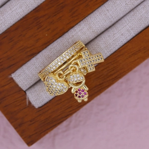 Detail of gold-plated ring with dangling heart, cross, and figure charms inset with zircons