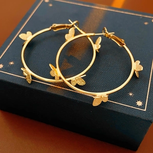 Détail de boucles d'oreilles créoles papillon dorées sur un coffret à bijoux bleu