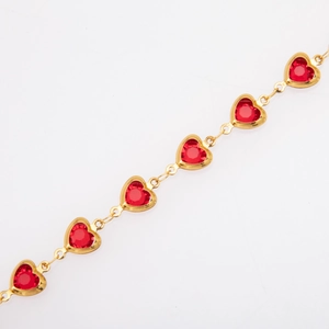 Detail of gold-plated chain link bracelet with red heart-shaped gemstone charms