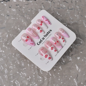 Detail of almond press-on nails featuring red lips, bows, and sparkling rhinestones