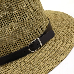 Gros plan sur la texture du chapeau de paille avec ruban en cuir et boucle argentée