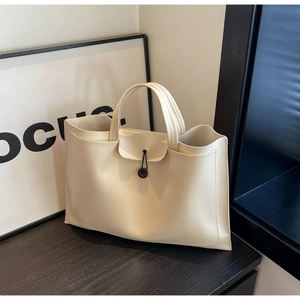 Detail view of cream tote bag with contrast button closure and clean stitched edges