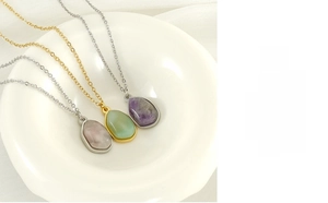 Detailed close-up of irregular natural stone pendants in purple, pink, and green on chains