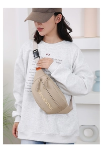 Detailed view of beige canvas chest bag with adjustable strap worn across a gray sweatshirt