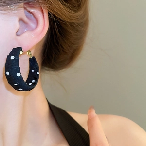Detailed view of polka dot fabric wrapped hoop earrings worn by a model in French style