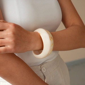 Close-up of white resin bangle with amber marble patterns on a model's wrist
