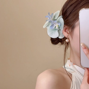 Detail showing gradient fabric flower hair clip with pearl center and matching earrings