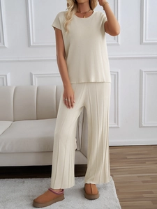 Detail von beige Kurzarm-Strickoberteil und plissierter Weithose an einem Modell