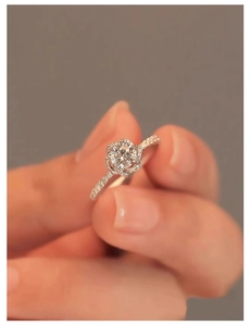 Macro view of floral diamond ring with a round center stone and pavé setting on a hand
