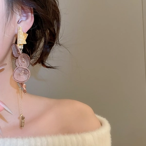 Close-up of elegant long tassel earring with brown petals and gold metal chain on a model