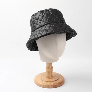 Detail of black quilted puffer bucket hat featuring classic diamond stitching on mannequin