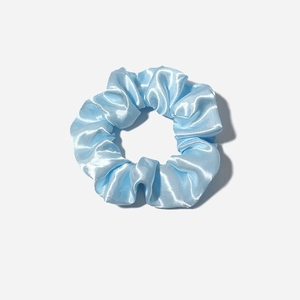 Light blue satin silk scrunchie with soft pleats and elegant sheen on grey background