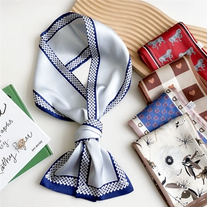 Elegant satin long skinny scarf with diverse floral and geometric patterns on a wooden tray