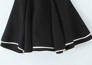 Close-up of tiered dress hem with black fabric and white contrast double-line piping