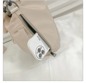 Detail of side zipper pocket on beige nylon bucket bag showing depth with phone
