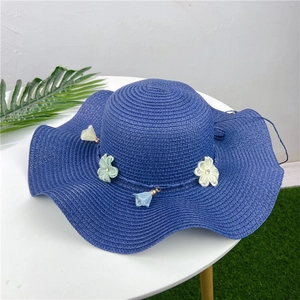 Close-up of dark blue woven sun hat with floral ornaments and decorative tassels