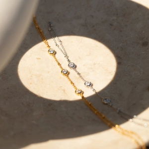 Eleganti bracciali in oro e argento con ciondoli in zircone su superficie in pietra naturale
