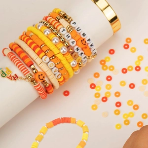 Détail de bracelets en perles d'argile jaunes et oranges avec perles PUMPKIN et HAPPY