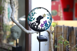 Detail of solar garden light with iron dog and butterfly silhouette among purple flowers