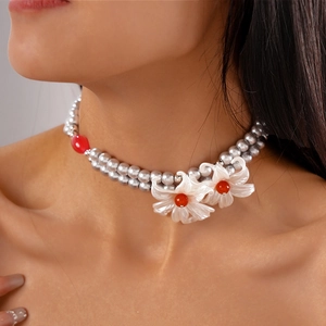 Detail of double-layer grey pearl necklace featuring artisanal white flower charms