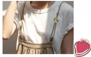 Close-up of strawberry wreath brooch with white pearl on a stylish striped pinafore