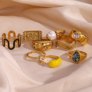 Collection of gold-plated rings with enamel and zircons on beige silk background