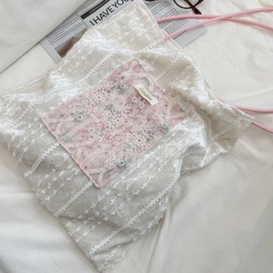 Detail of pink floral square pocket with white lace and logo tag on canvas tote bag