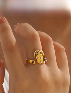 Detail view of a gold-plated irregular ring with white pearl inlays on a model's finger