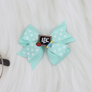Close-up of mint green polka dot bow hair clip with ABC blackboard and apple charm