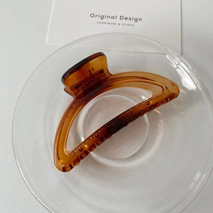 Detailed close-up of an amber resin hair claw clip in a minimalist elegant design