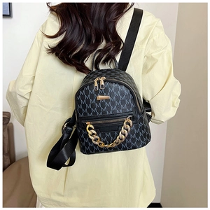 Close-up of mini backpack showing textured M-print leather and golden chain detail