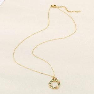 Detail of a golden Christmas wreath necklace with green enamel and sparkling rhinestones