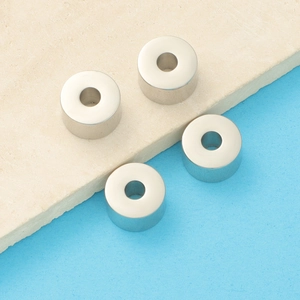 Detailed view of four silver cylindrical metal beads for DIY necklace and bracelet jewelry