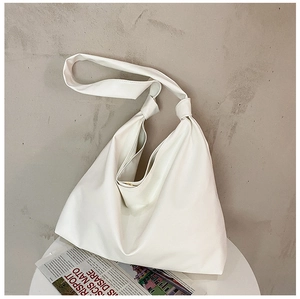 Detailed view of white pleated dumpling tote bag on a minimalist white table surface