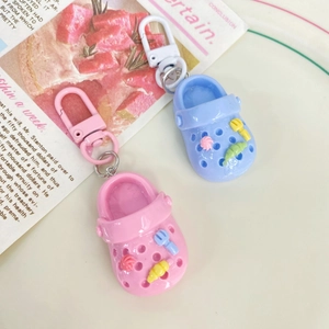 Close-up of pink and blue mini clog shoe keychains with decorative charms and metal rings