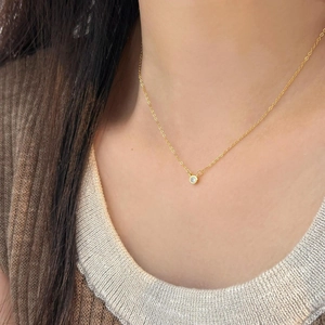 Detail of minimalist 925 silver gold necklace with a single bezel-set zircon on model