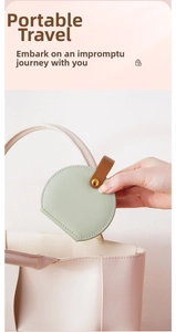 Close-up of mint green leather jewelry case being placed into a pink handbag for travel
